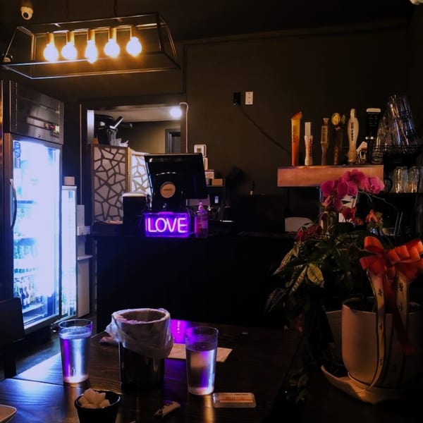 Interior of Mr. Dak, a Korean restaurant, with a neon 'LOVE' sign, bar, and dining table.